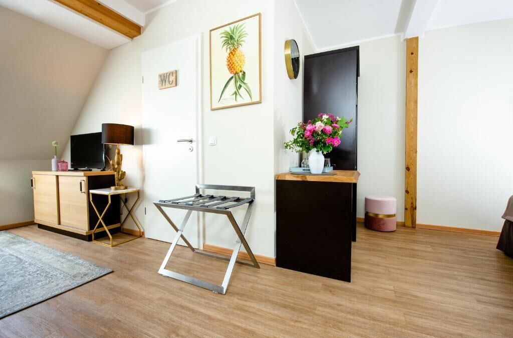 A room with a wooden ceiling, a black cabinet, a metal-framed table, a TV, and a framed pineapple artwork.