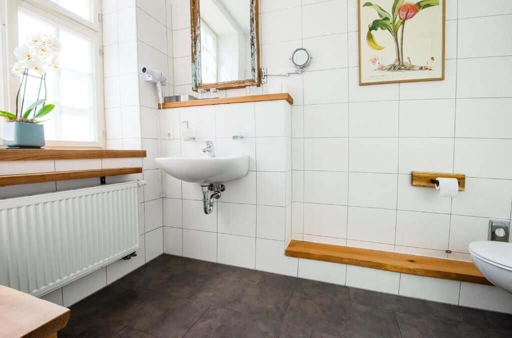 Ein Badezimmer mit Waschbecken, Holzregalen, Heizkörper und Toilette.