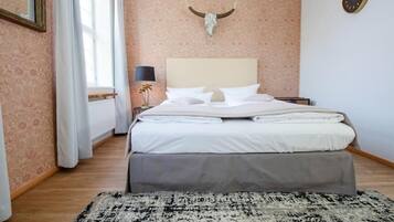 Een slaapkamer met een groot bed, een hoofdbord, een hangklok en een decoratie van een stierenhoofd.