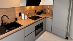 A modern kitchen with a black sink, stainless steel appliances, and a built-in oven. - New vacation home on the outskirts (Eupen)
