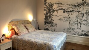 Una camera da letto con un letto, lampade da comodino, un comodino e un affresco sulla parete.