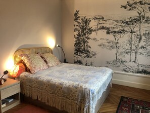 A bedroom with a bed, bedside lamps, a nightstand, and a wall mural. - Appartement 60m² 1 chambre, parking et piscine (Aix-les-Bains)