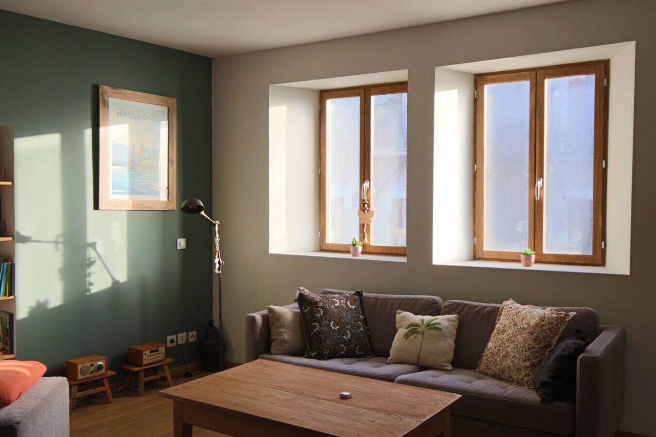 Una sala de estar con sofá, una mesa de centro y dos ventanas con persianas.