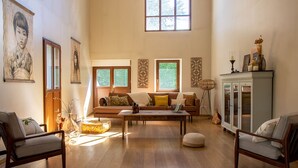 Uma sala de estar ampla com piso de madeira, um conjunto de sofá, uma mesa de centro e um armário.