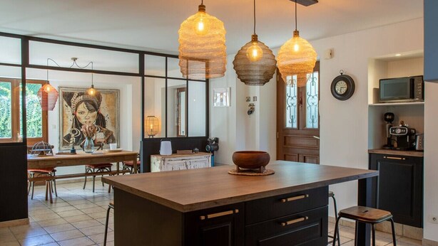 Cozinha moderna com uma ilha grande, luminárias pendentes e um espaço de refeições com um mural.