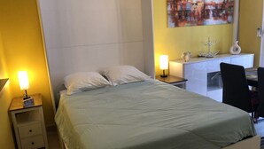 Un dormitorio con cama, mesitas de noche, un escritorio y una silla.
