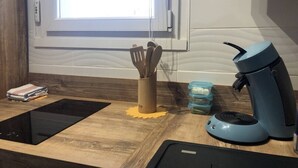 Una cocina con cafetera, un tarro para cuchillos y una tableta sobre una encimera de madera.