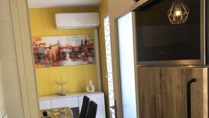 Una cocina compacta con un armario de madera, una mesa de comedor con sillas y un cuadro en la pared.