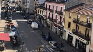 Vista de una calle con edificios, coches estacionados y cielo despejado.