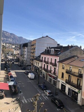 A street view with buildings, parked cars, and a clear sky. - Studio 38m², parking et terrasse, en centre-ville (Aix-les-Bains)