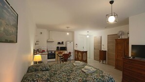 Un dormitorio con cama, lámpara de noche, cómoda y televisor.