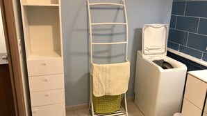 Un área de lavandería con un tendedero, una lavadora y un armario.