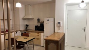 Cocina compacta con comedor, horno integrado, microondas y refrigerador.