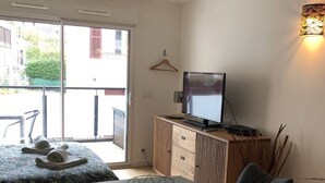 Habitació moderna amb taula de dinar, cadires, televisió i un armari.
