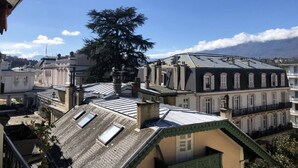 A view of a cityscape with buildings, including a prominent tree and a building with a sloped roof. - Studio 25m², avec parking et balcon, centre-ville (Aix-les-Bains)