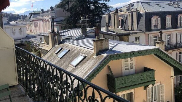A balcony with a view of a tree and buildings. - Studio 25m², avec parking et balcon, centre-ville (Aix-les-Bains)