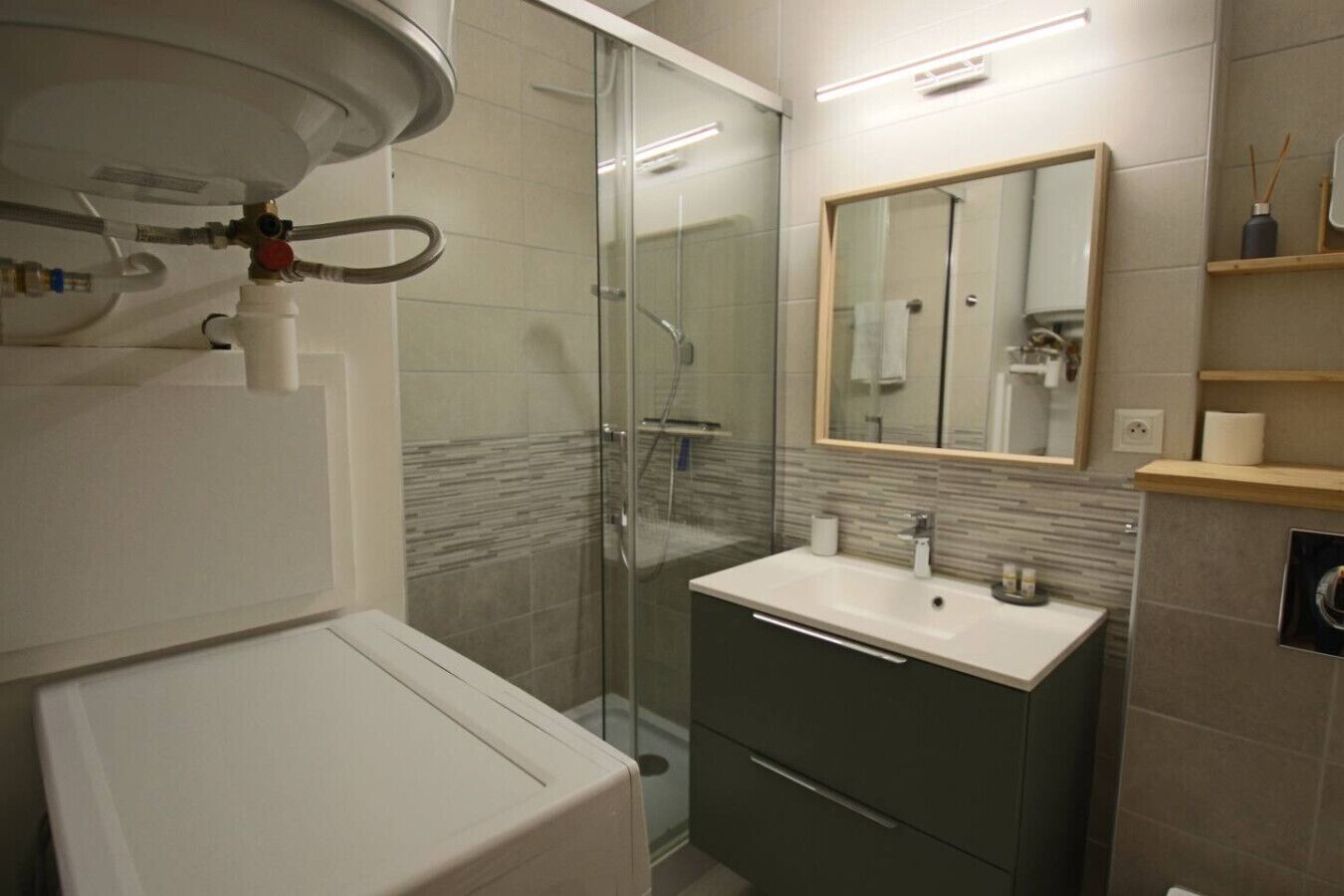 Ein modernes Badezimmer mit Duschkabine aus Glas, einem weißen Waschbecken und einem Spiegel über dem Waschtisch.