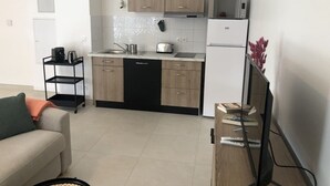 A modern kitchen with wooden cabinets, a black dishwasher, and a white refrigerator. - Appartement 46m² 1 chambre, parking, proche du lac (Aix-les-Bains)