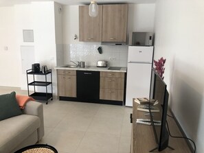 Eine moderne Küche mit Holzschränken, einem schwarzen Geschirrspüler und einem weißen Kühlschrank.