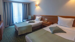A hotel room with two beds, a desk, a chair, a lamp, and a window with curtains. - Özkaymak Otem Hotel -Ultra All Inclusıve (Kemer)
