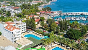 An aerial view of a coastal town with a marina, a swimming pool, and residential buildings. - Özkaymak Otem Hotel -Ultra All Inclusıve (Kemer)