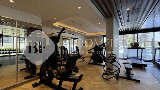 A gym with exercise equipment, large windows, and a modern interior design.