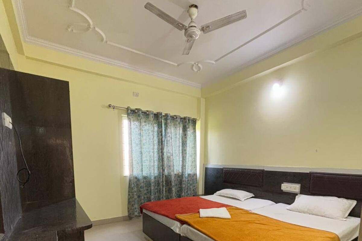A bedroom with a bed, a ceiling fan, a window with curtains, and a dark-colored wardrobe.