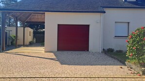 Ett hus med en röd garageport, en inglasad veranda och en asfalterad uppfart.