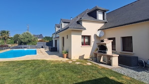 En bostadsfastighet med en swimmingpool, ett område för grillning och en välskött gräsmatta.