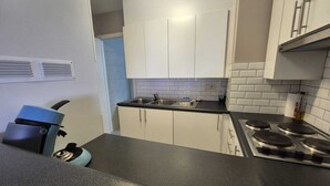 Une cuisine avec des meubles blancs, un plan de travail noir et une cuisinière.