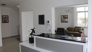 A modern office with a reception desk, a black office chair, a brown sofa, and a large window. - Vista Mar (Tarrafal)