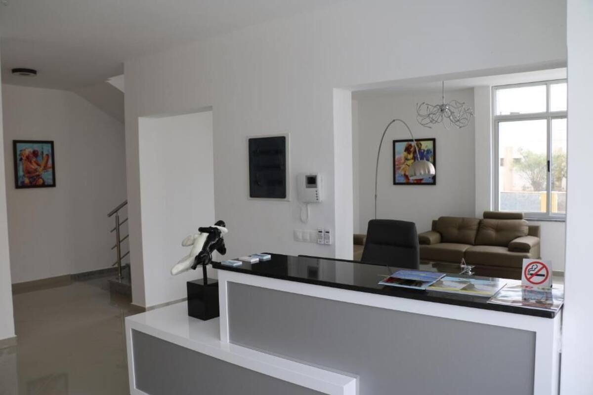 Una oficina moderna con un mostrador de recepción, una silla de oficina negra, un sofá marrón y un ventanal grande.