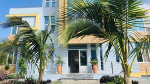 A modern hotel with a two-story structure, large windows, and a well-maintained garden with palm trees. - Vista Mar (Tarrafal)