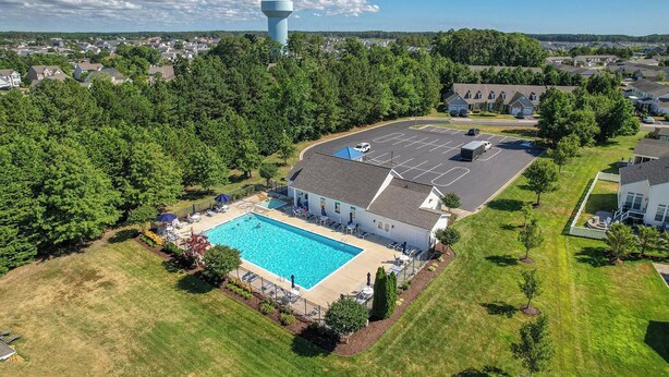 An aerial view of a residential area with a swimming pool, a parking lot, and a water tower in the background. - Minutes from Fenwick Island & North Ocean City Beaches, Pelicans Perch a 3 bed, 2.5 bath Beautiful Home with Community Pool & Free WIFI (Selbyville)