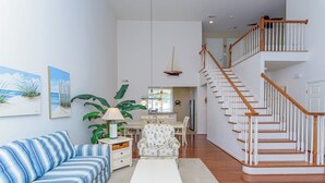 A spacious living room with a striped sofa, a white coffee table, and a staircase leading to an upper floor. - Minutes from Fenwick Island & North Ocean City Beaches, Pelicans Perch a 3 bed, 2.5 bath Beautiful Home with Community Pool & Free WIFI (Selbyville)