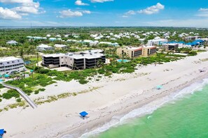 Ein Küstenhotelbereich mit mehreren Gebäuden, einem Strand und freiem Blick auf das Meer.