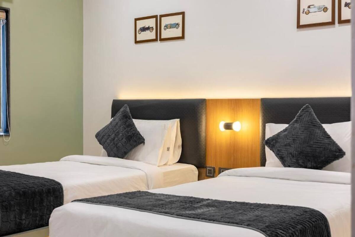 A hotel room with two beds, a wooden headboard, and wall-mounted lights.