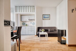 Ein kompakter Wohnbereich mit Küchenzeile, einer Couch, einem Essbereich und einem kleinen Tisch.