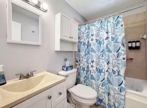 A bathroom with a sink, toilet, and shower curtain. - Manatee Meadows (Crystal River)