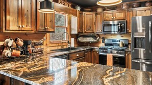 A kitchen with wooden cabinets, a granite countertop, stainless steel appliances, and pendant lighting. - Welcome to Pine and Buck Lodge, a perfect 3 bedroom 2.5 bathroom get away (Ellijay)