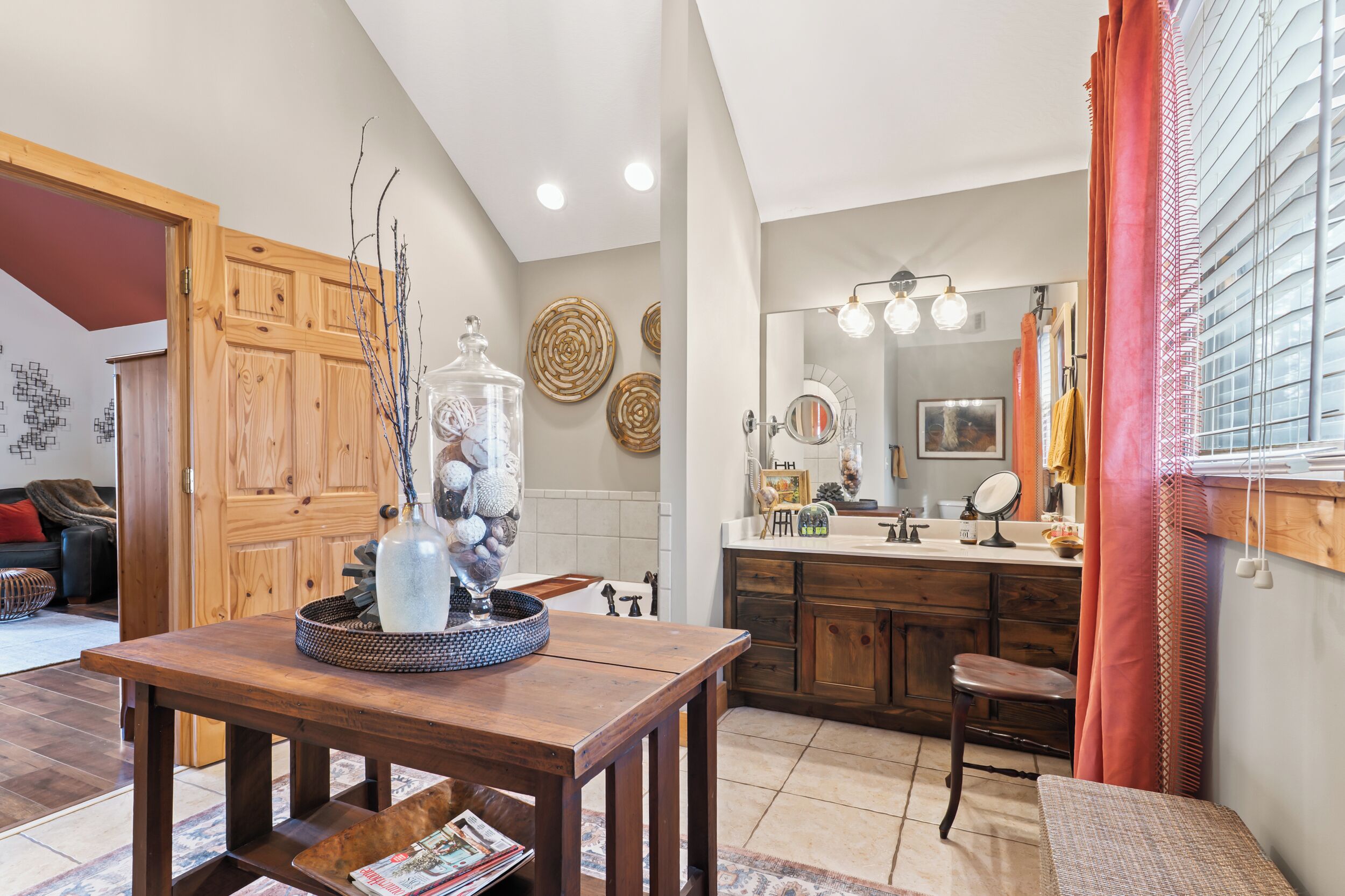 Una cocina moderna con armarios de madera, una mesa de comedor con un florero y un ventanal con cortinas.