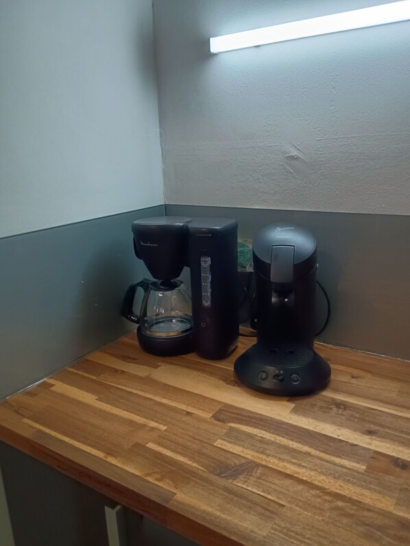 Una encimera de cocina con una cafetera, una balanza y un hervidor.