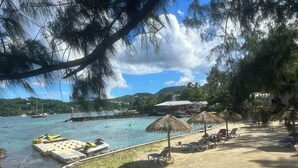 Ein Strand mit Liegestühlen, einer Anlegestelle und einem Boot.