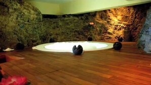 Ein Zimmer mit Holzboden, einer runden Sitzecke und einer Steinwand.