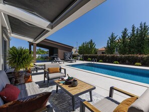 Ein Poolbereich mit Liegestühlen, einem Tisch und einer Sitzecke mit Kissen.