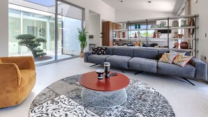 Una sala de estar moderna con un sofá gris, una mesa de centro redonda y un ventanal grande.