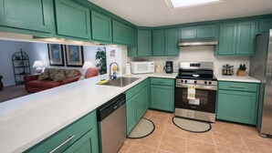 A compact kitchen with teal cabinets, a stainless steel oven, and a white countertop. - Renovated 1st Floor Beach 250ft Pool 2 Bedroom Apts (South Padre Island)