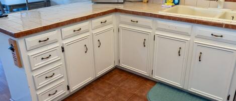 A kitchen with white cabinets, a microwave, a sink, and a green rug.