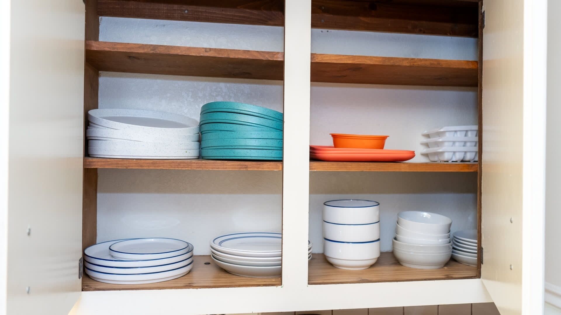 A kitchen cabinet with shelves holding various plates and bowls.
