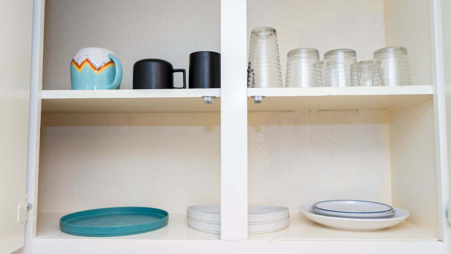 A kitchen cabinet with shelves containing various kitchenware items.